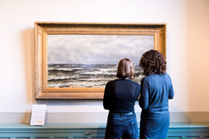 Two visitors are looking at a painting in The Mesdag Collection